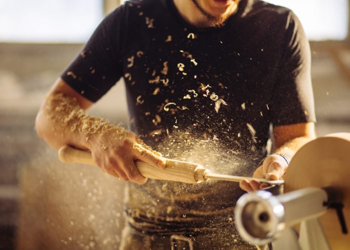 Turner working on a lathe in the workshop. Male hand carved wooden blank