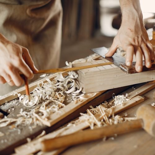 Man working with a wood. Carpenter in a white shirt